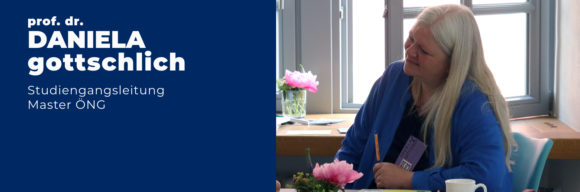 Professorin Doktorin Daniela Gottschlich ist Studiengangsleiterin des Masters Ökonomie - Nachhaltigkeit - Gesellschaftsgestaltung. Sie sitzt an einem Tisch, auf dem rosa Blumen stehen, und lächelt. Sie trägt eine blaue Bluse und hat weiße lange Haare.