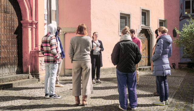 Acht Personen stehen auf einem öffentlichen Platz und führen gemeinschaftlich eine Zukünftebildung durch.