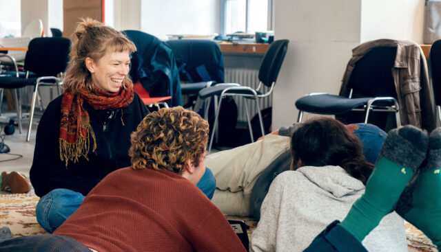 Drei Studierende sitzen auf dem Boden, lachen und haben gute Laune bei einem 4FutureLab im Bistro der Hochschule für Gesellschaftsgestaltung (HfGG).