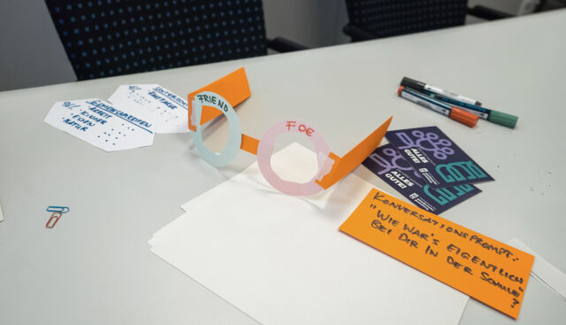 Bei 4FutureLabs Workshops wird kreativ gearbeitet: Auf diesem Ausschnitt sind eine aus Pappe selbst gebastelte Brille, Papier, Eddings, Marker und Karteikarten abgebildet.
