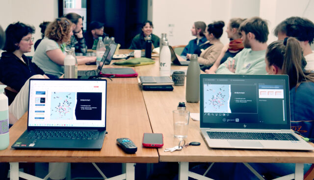 An vier Tischen eines Seminarraums sitzen 13 Studierende, welche einen 4FutureLab Workshop zur Zukünftebildung gemeinsam durchführen.
